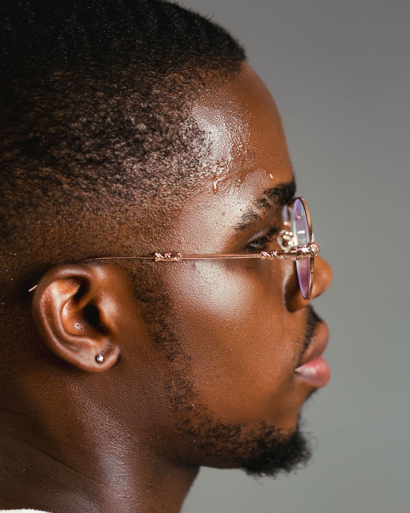 A man in profile wearing gold metal glasses